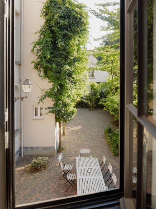 Courtyard with ivy-covered walls, white dining furniture, and brick patio at Castanea Business & Suites in Merelbeke-Melle