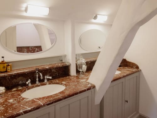 Luxurious bathroom at Castanea Business & Suites with marble countertops, dual sinks, oval mirrors, and elegant fixtures in