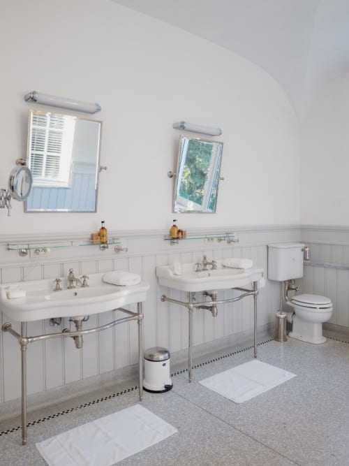 Elegant dual-sink bathroom at Castanea Business & Suites, Merelbeke with vintage fixtures and white subway tile wainscoting