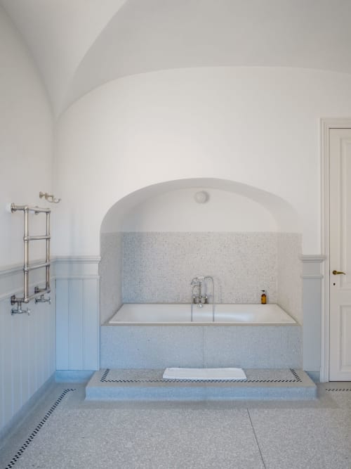 Luxury bathroom with curved white walls, mosaic tiled soaking tub, heated towel rack at Castanea Business & Suites, Merelbeke