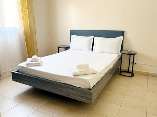 Chambre moderne de l'appartement DakarByDays à Dakar avec lit queen, draps blancs, tête de lit foncée et climatisation