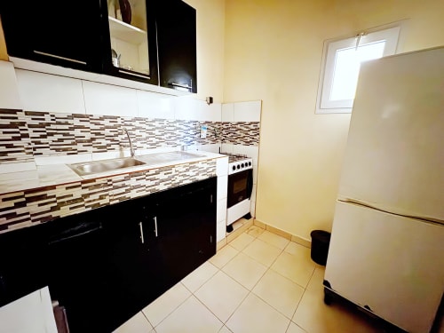 Cuisine moderne de l'appartement DakarByDays avec armoires noir et blanc, dosseret géométrique et appareils en acier inoxydable