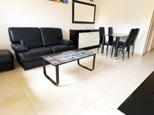 Salon moderne avec canapé en cuir noir, table basse et salle à manger dans l'appartement DakarByDays, Dakar Almadies