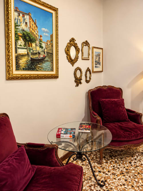 Venetian-inspired luxury apartment with burgundy velvet chairs, ornate gold mirrors, and Italian canal painting at Luxury