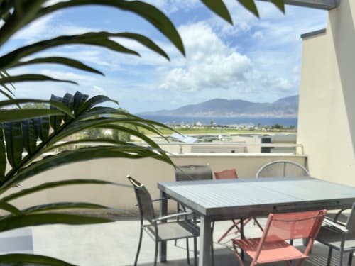 Terrasse sur toit de la VillaSerenita à Porticcio avec vue mer, table à manger, transats et plantes en pot