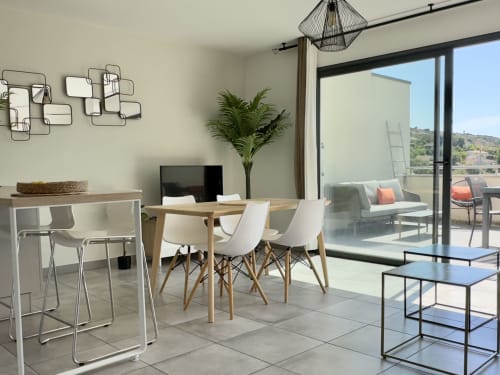 Séjour moderne de VillaSerenita Porticcio avec vue mer, table à manger, chaises blanches et accès balcon