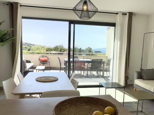 Terrasse moderne à Porticcio avec vue mer, coin repas, salon et paysage montagneux au-delà de la balustrade