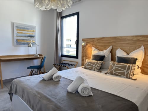 Chambre moderne à VillaSerenita Porticcio avec deux lits, têtes de lit en bois, bureau, vue mer et décoration contemporaine