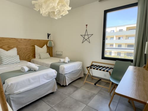 Chambre moderne à VillaSerenita à Porticcio avec lits jumeaux, tête de lit en bois, vue sur la mer, bureau de travail et