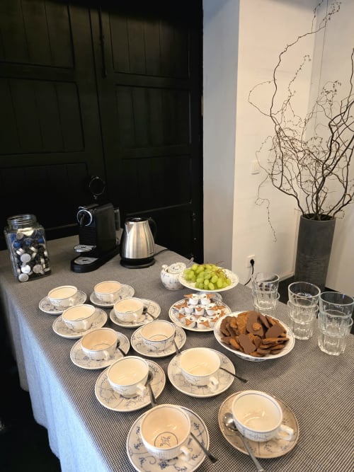 Elegant tea service setup at Castanea Business & Suites with porcelain cups, pastries, fresh grapes, and decorative branches