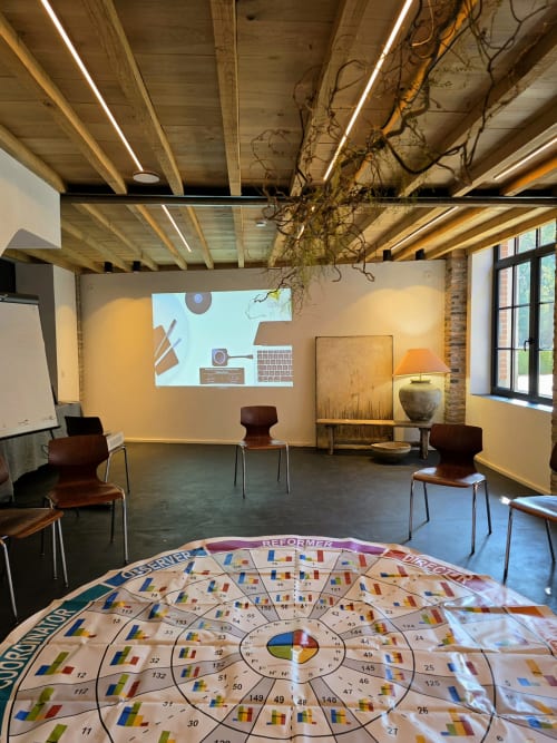 Modern meeting room at Castanea Business & Suites with board game floor, wooden ceiling beams, and projection screen in