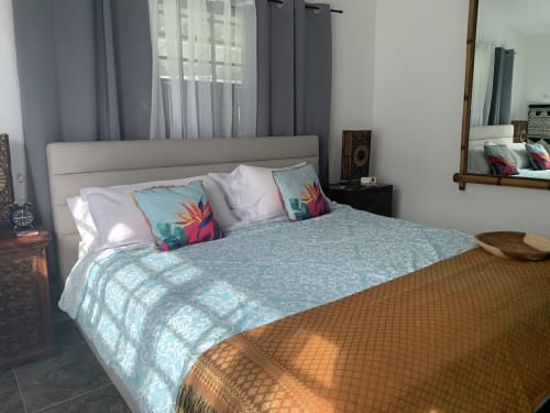 Modern bedroom at El Litoral Wellness Retreat with queen bed, turquoise patterned bedding, colorful throw pillows, and garden