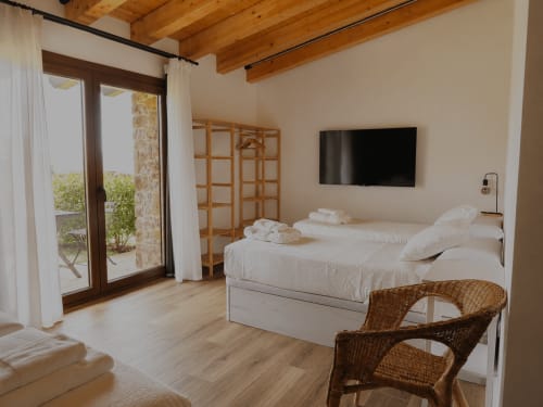 Amplia habitación cuádruple en Hotel Rural Izarbe de Burgos con acceso al jardín, vigas de madera, camas gemelas y puertas hacia la terraza