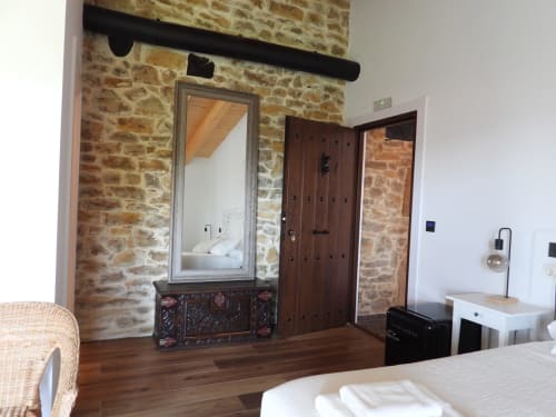 Habitación del Hotel Rural Izarbe en Burgos con muros de piedra, puerta de madera, espejo y acceso a vista del jardín