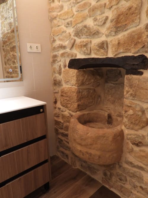 Baño rústico con piedra vista en el Hotel Rural Izarbe de Burgos, lavabo de piedra labrada y mueble vanitory moderno