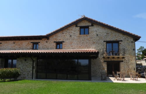 Edificio de piedra del Hotel Rural Izarbe con terraza y jardín verde en Burgos, España