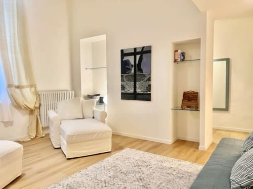Soggiorno moderno in storico appartamento bolognese con arredi color crema, pavimenti in legno e arte contemporanea