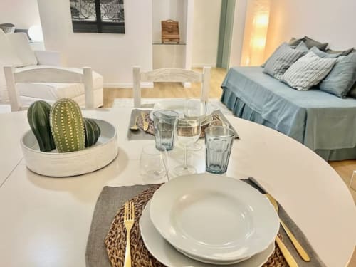 Moderno monolocale presso Living Palazzi Storici Bologna con tavolo da pranzo, coperto, cactus in vaso e letto visibile