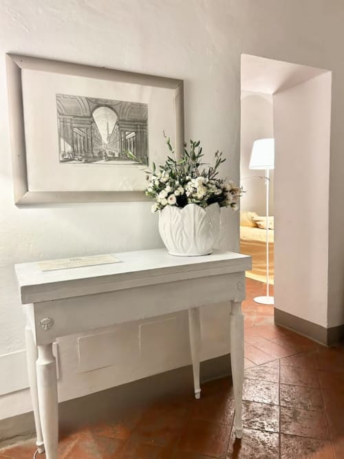 Elegante ingresso di Living Palazzi Storici a Bologna con consolle bianca, composizione floreale e sketch architettonico.