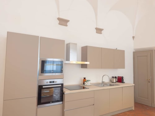 Cucina moderna nell'appartamento bolognese Living Palazzi Storici con mobili beige, elettrodomestici in acciaio inox e archi
