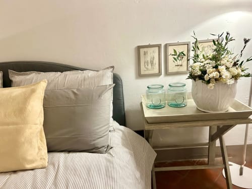 Elegante camera da letto in un appartamento di palazzo storico a Bologna con biancheria a righe, composizione floreale e opere botaniche
