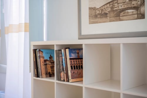 Scaffale bianco con libri di viaggio sulle città italiane nell'appartamento di Bologna presso Living Palazzi Storici
