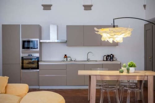 Cucina moderna con mobili grigi, tavolo da pranzo in legno e lampada a sospensione gialla nell'appartamento di Bologna presso Living Palazzi
