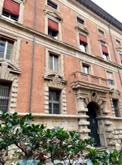 Palazzo storico in mattoni a Bologna con arco, tende rosse e dettagli architettonici italiani al Living