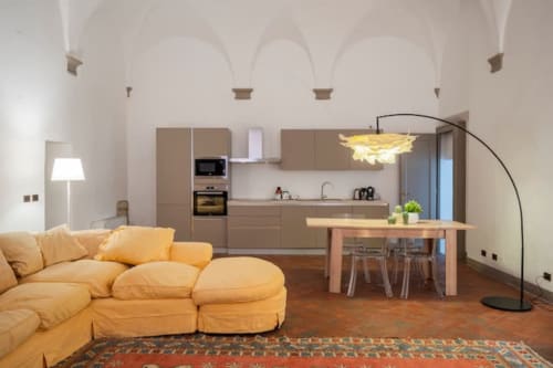 Moderno appartamento open-plan nel palazzo storico di Bologna con divano giallo, tavolo in legno e cucina contemporanea