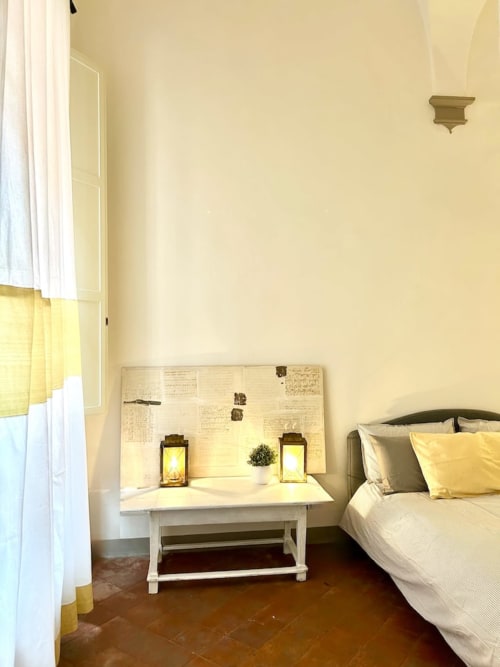 Accogliente camera da letto a Living Palazzi Storici Bologna con letto, scrivania bianca, dettagli gialli e arredamento storico