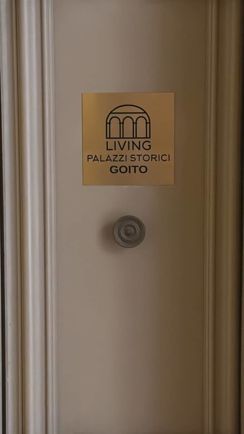 Targa d'ingresso Palazzi Storici Goito su porta beige, appartamento storico a Bologna