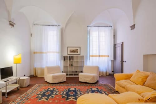 Ampio salotto in palazzo storico bolognese con soffitti affrescati, arredi gialli e pavimenti in cotto.