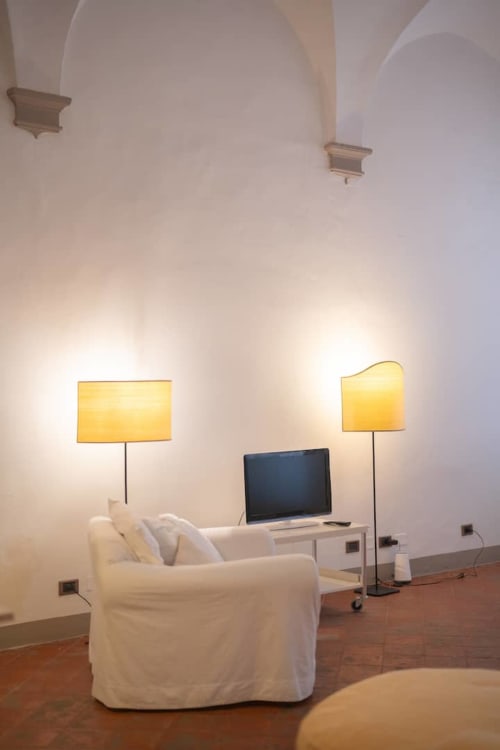 Moderno salotto in un appartamento storico a Bologna con poltrona bianca, scrivania, laptop e lampade da terra gialle