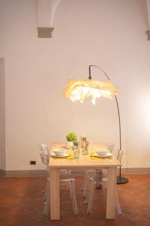 Elegante tavolo da pranzo in appartamento bolognese con tavolo in legno, lampada ad arco moderna e mise en place