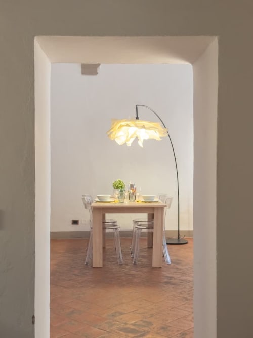 Moderna sala da pranzo nell'appartamento bolognese con lampada ad arco, tavolo in legno chiaro e sedie trasparenti