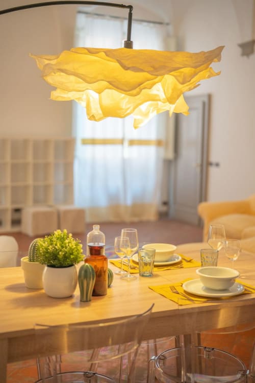 Tavolo da pranzo elegante a Living Palazzi Storici a Bologna con lampada sospensione gialla e posate