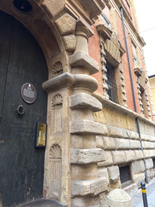 Facciata storica di palazzo bolognese con colonne in pietra ornate e motivi decorativi a conchiglia presso Living Palazzi Storici