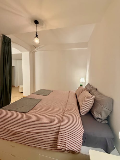 Camera moderna a Living Palazzi Storici Bologna con biancheria a righe, lampada a sospensione e arredamento minimalista