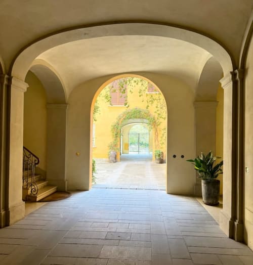 Passaggio ad arco nel palazzo storico di Bologna con pavimenti in cotto e ingresso della corte ricoperto di edera