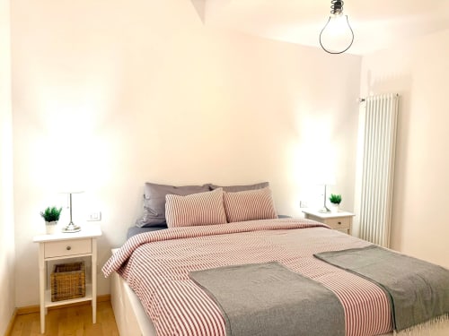 Bright bedroom at Living Palazzi Storici Bologna with striped bedding, side tables, radiator and pendant light