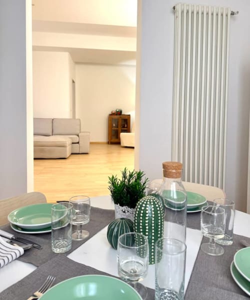 Elegante tavolo da pranzo con piatti verdi e composizione di cactus affacciata sul living a Living Palazzi Storici, Bologna