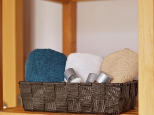 Cesta tejida con toallas dobladas y artículos de aseo en un apartamento del hotel Apartamentos La Machacona, Cáceres