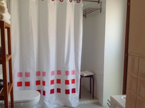 Cortina de ducha a cuadros blanca y roja en el baño moderno del apartamento La Machacona en Cáceres, España