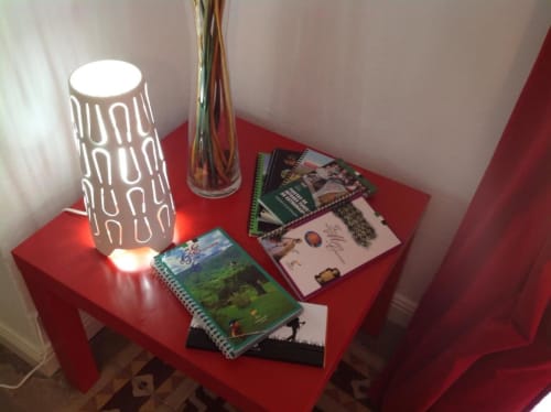 Mesita auxiliar roja en apartamento de Cáceres con lámpara decorativa, jarrones y guías de viaje