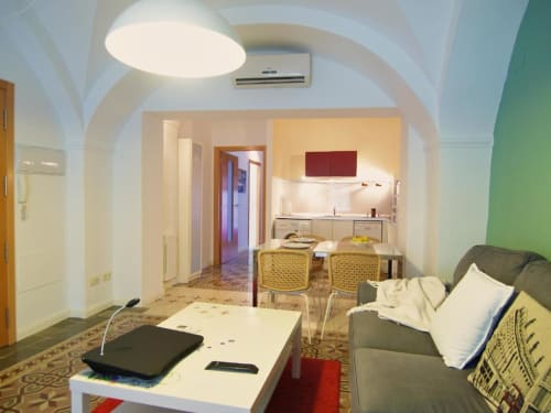 Moderno apartamento de 1 dormitorio en Cáceres con sala abierta, cocina americana, comedor, sofá y techos abovedados.