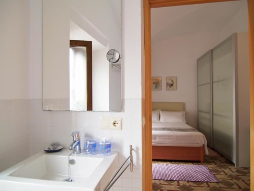 Baño con lavabo y espejo en el apartamento Plaza de Santiago de Apartamentos La Machacona, Cáceres, con vista al dormitorio