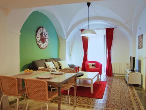 Luminoso apartamento diáfano en La Machacona, Cáceres, con pared verde, comedor, detalles rojos y techo abovedado