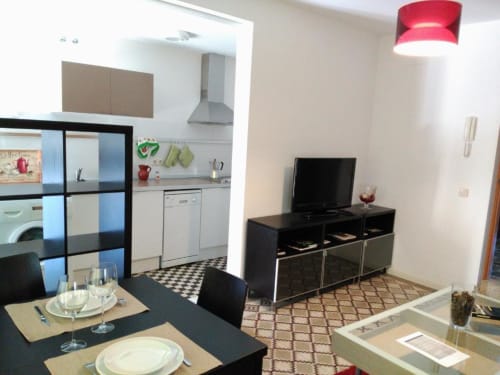 Moderno apartamento en Cáceres con sala de estar, comedor y cocina abierta, equipado con televisor, mesa de comedor y muebles contemporáneos