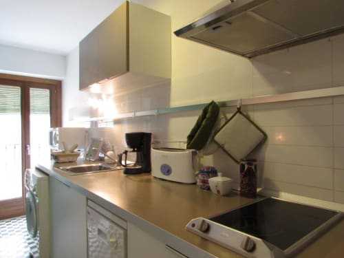 Cocina moderna en apartamento de Cáceres con armarios amarillos, salpicadero de azulejos blancos y electrodomésticos