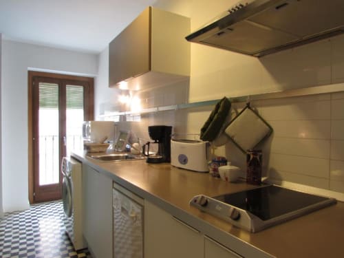 Moderno kitchenette en apartamento de Cáceres con muebles color crema, electrodomésticos de acero inoxidable y piso de azulejos